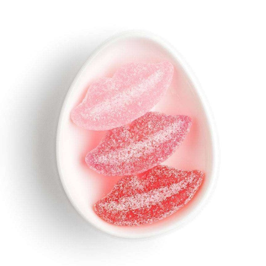 Three gummy candy lips on white ceramic dish.