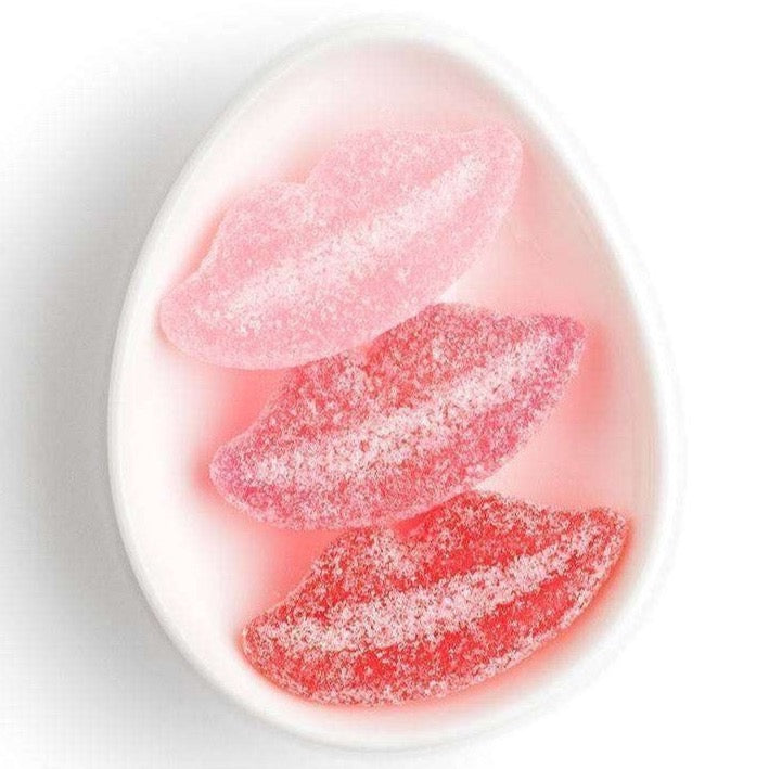 Three gummy candy lips on white ceramic dish.
