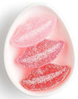 Three gummy candy lips on white ceramic dish.