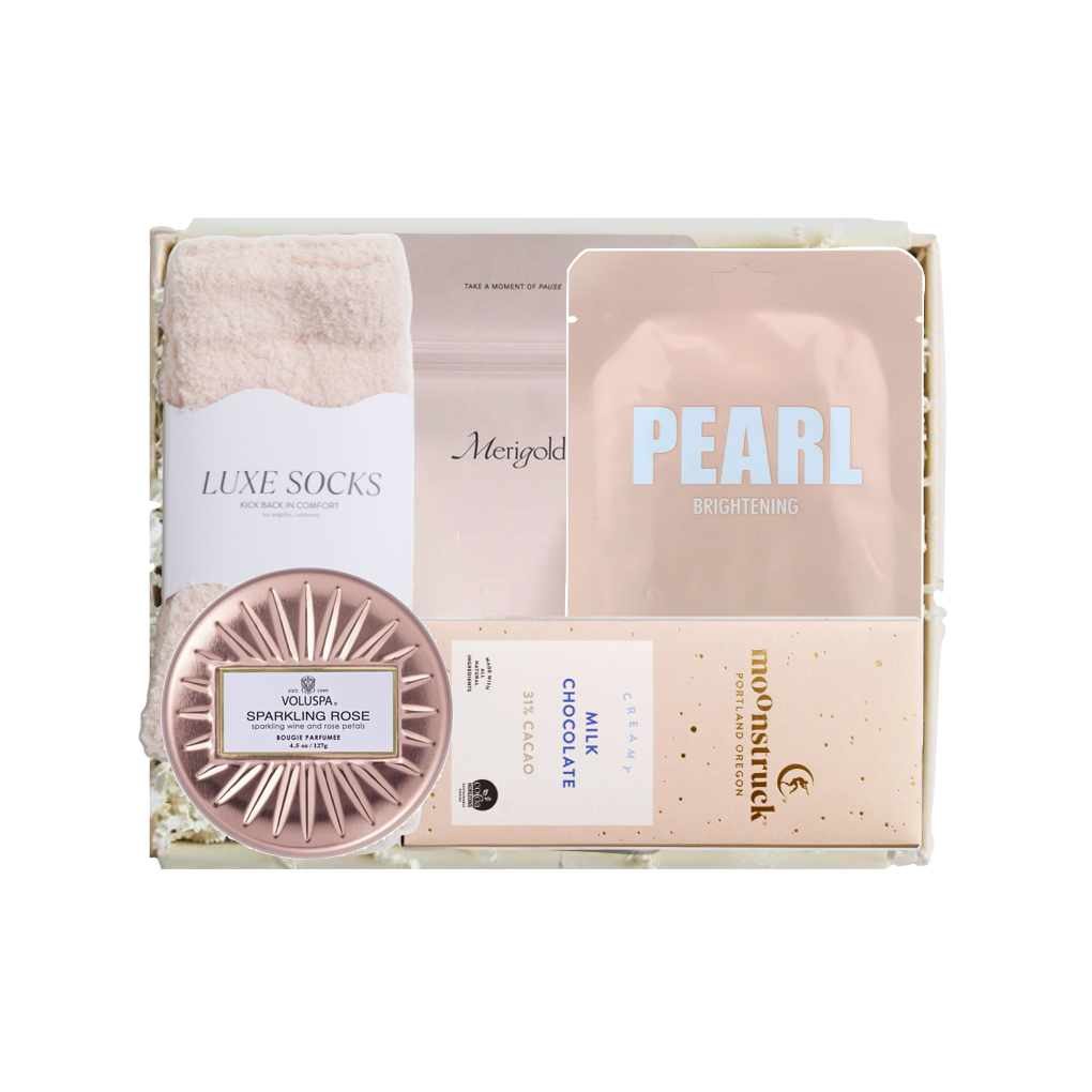 A curated beauty gift set in a white box, featuring a pink towel, a sheet mask labeled 'PEARL BRIGHTING', a rose gold sparkling rose scrub, a chocolate bar, and a moisturizer from the brand moenstruck.