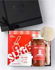 BOXFOX Black gift box packed with "Slice" Pizza book, wood pizza cutter, Ciao Pappy Marinara sauce, Pizza herbs jar and plaid red Geometry tea towel.