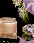 pale pink candle surrounded by flowers on a black background