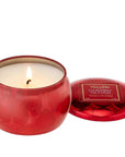 shiny red tin small round candle lit. lid is off to the side