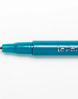 A close-up of a teal blue Le Pen fine liner pen with its fine tip visible, positioned horizontally on a clean white background.