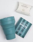 The inside of the SNOW ON THE BEACH curated box: white tea sachet, sea salt caramels and a teal stojo bottle shown open.