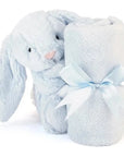 pale blue stuffed bunny with small blanket rolled in front of it. Looks like the bunny is holding blanket. blanket has blue bow tied on it