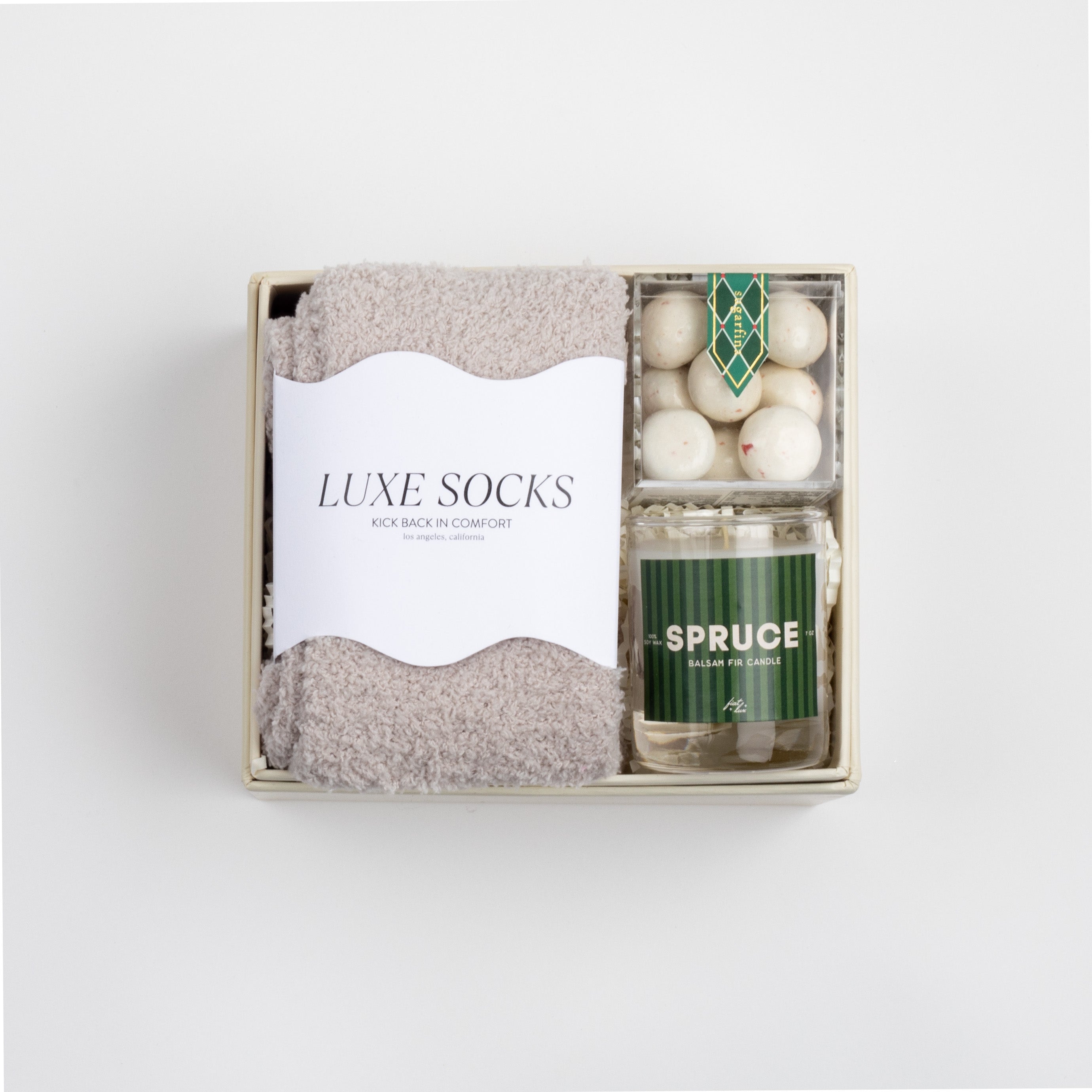 CREME BOXFOX box open with grey socks, peppermint crunch candy and a candle labeled in the scent &quot;SPRUCE.&quot;