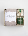 CREME BOXFOX box open with grey socks, peppermint crunch candy and a candle labeled in the scent "SPRUCE."