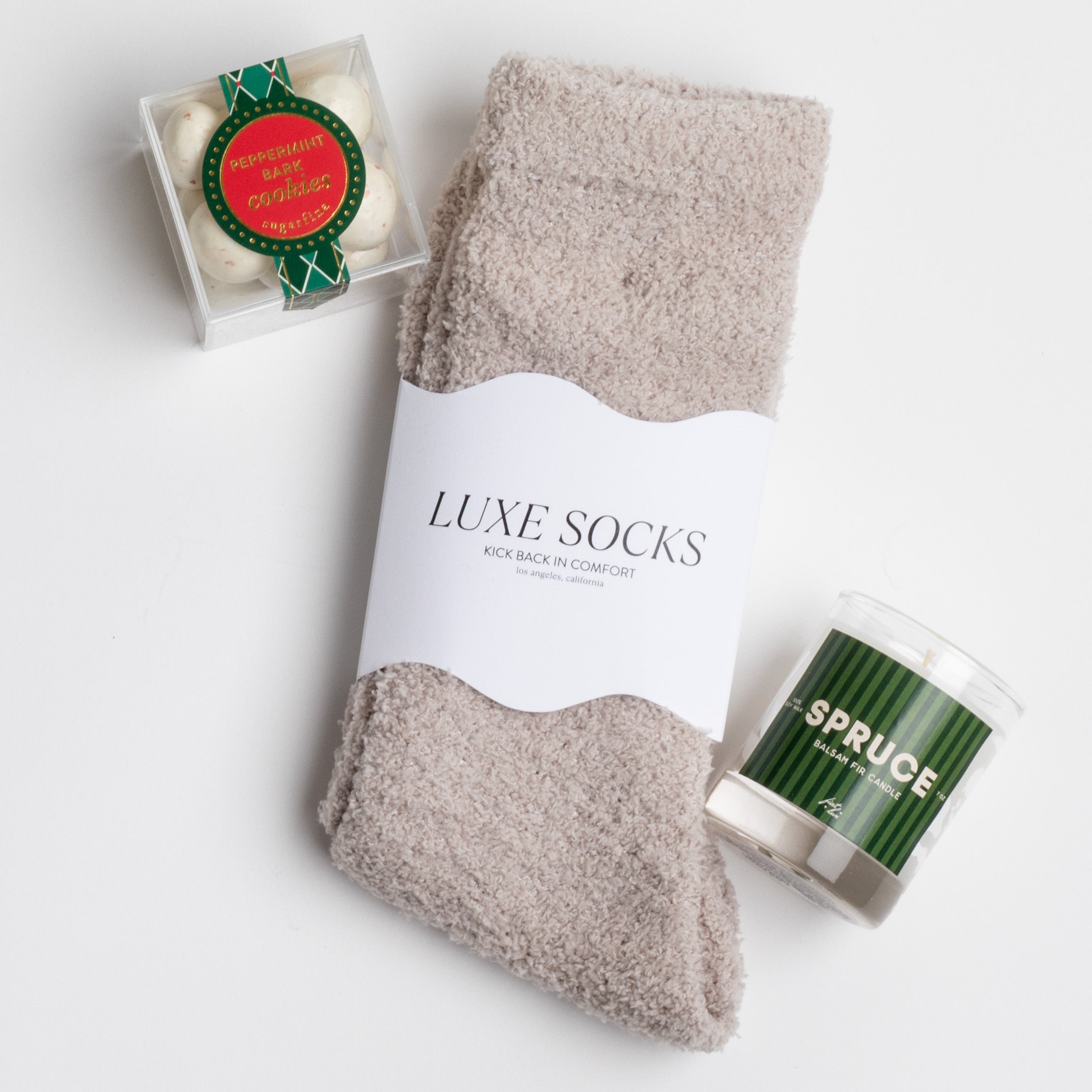 SPRUCE curated box items displayed: grey socks, peppermint crunch candy and a candle labeled in the scent "SPRUCE."