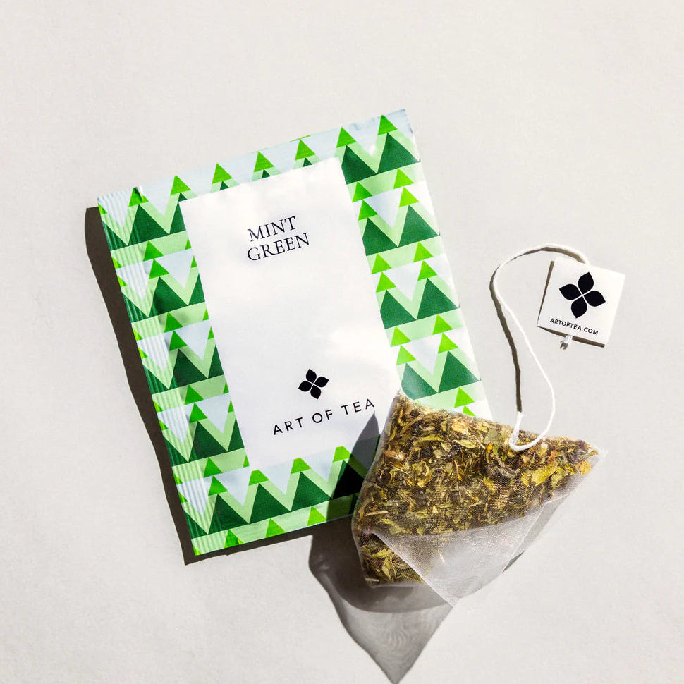Tea package with green triangle design and 'Art of Tea' branding on a light gray background