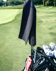 The product is shown hanging on golf clubs on a golf course