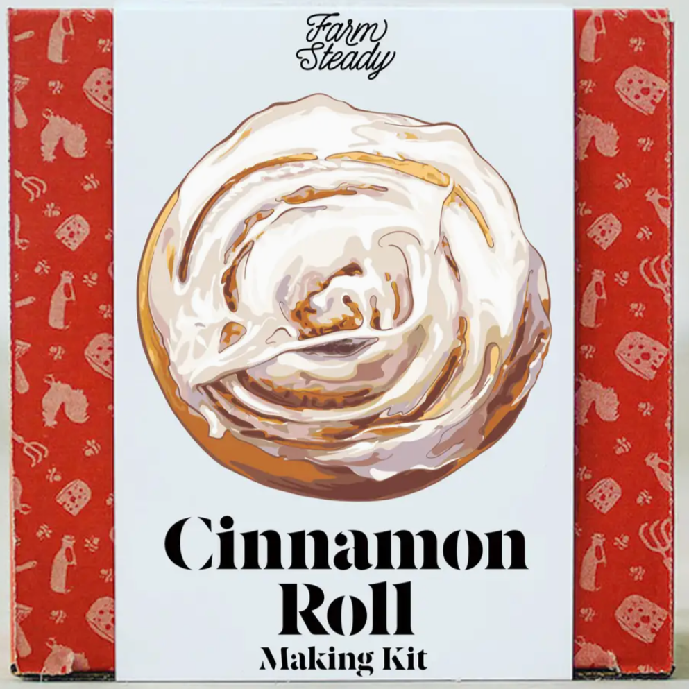 Cinnamon Roll making kit that has red and white packaging. The cinnamon roll is front and center on the package, featuring the white icing.