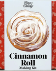 Cinnamon Roll making kit that has red and white packaging. The cinnamon roll is front and center on the package, featuring the white icing.