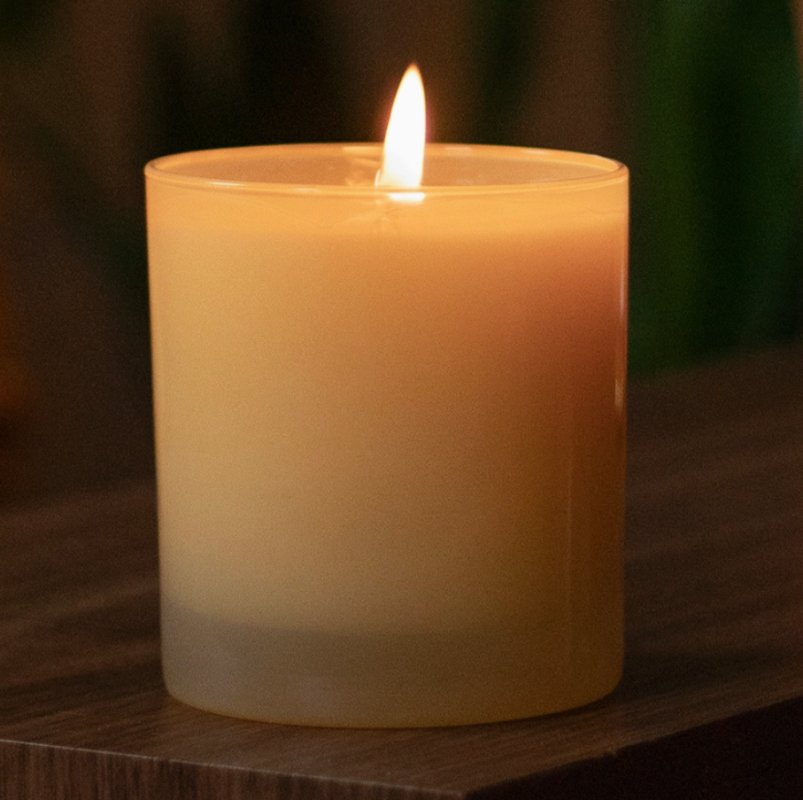 yellow glass candle burning on brown wooden table 