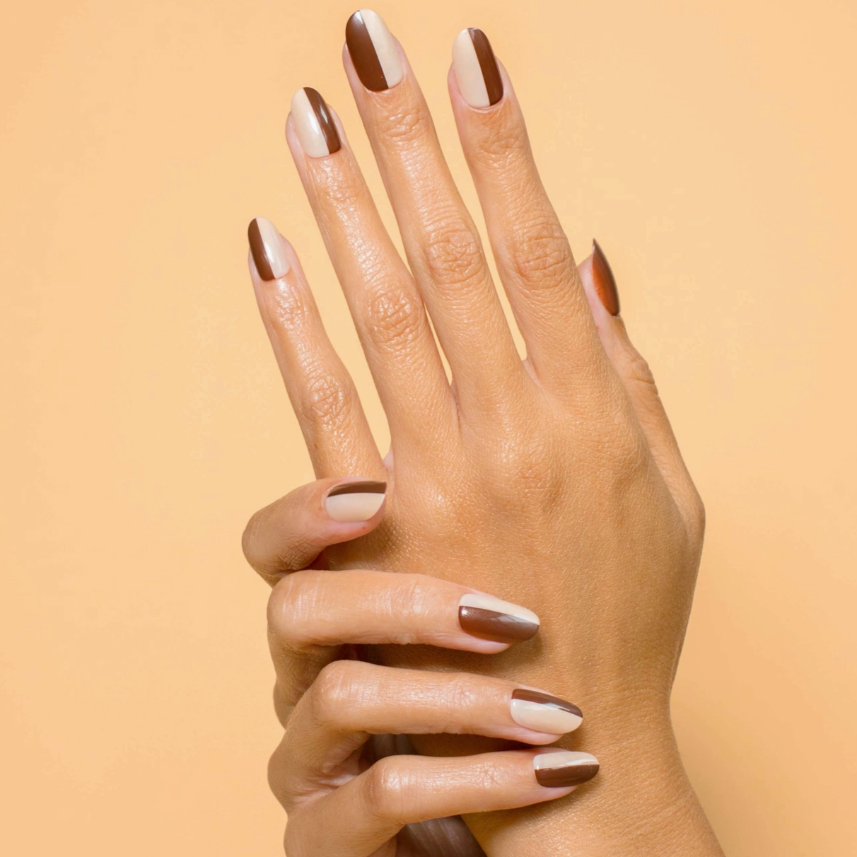 half brown half beige manicured nails behind beige background 