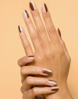 half brown half beige manicured nails behind beige background 