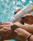 The sunscreen is shown being applied on a hand. The background is water.