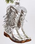 metallic glass cowboy boot ornament with brown bottoms on white background hanging from christmas tree on white background 