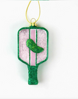 this image shows a pickleball racket shaped ornament, it is glittery with a green glittery pickle in the middle, green light pinks and whites are the main colors behind white background 