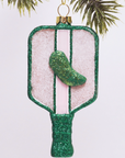 this image shows a pickleball racket shaped ornament, it is glittery with a green glittery pickle in the middle, green light pinks and whites are the main colors 