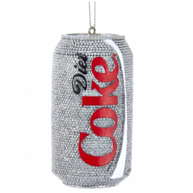 This image shows a sparkling, jewel-encrusted ornament shaped like a Diet Coke can. The can is covered with small, shiny crystals, giving it a glamorous, glittery look. The iconic "Diet Coke" branding, with its red and black lettering, is clearly visible. A small loop with a string at the top suggests that this ornament is designed to be hung, possibly as a decorative piece.


