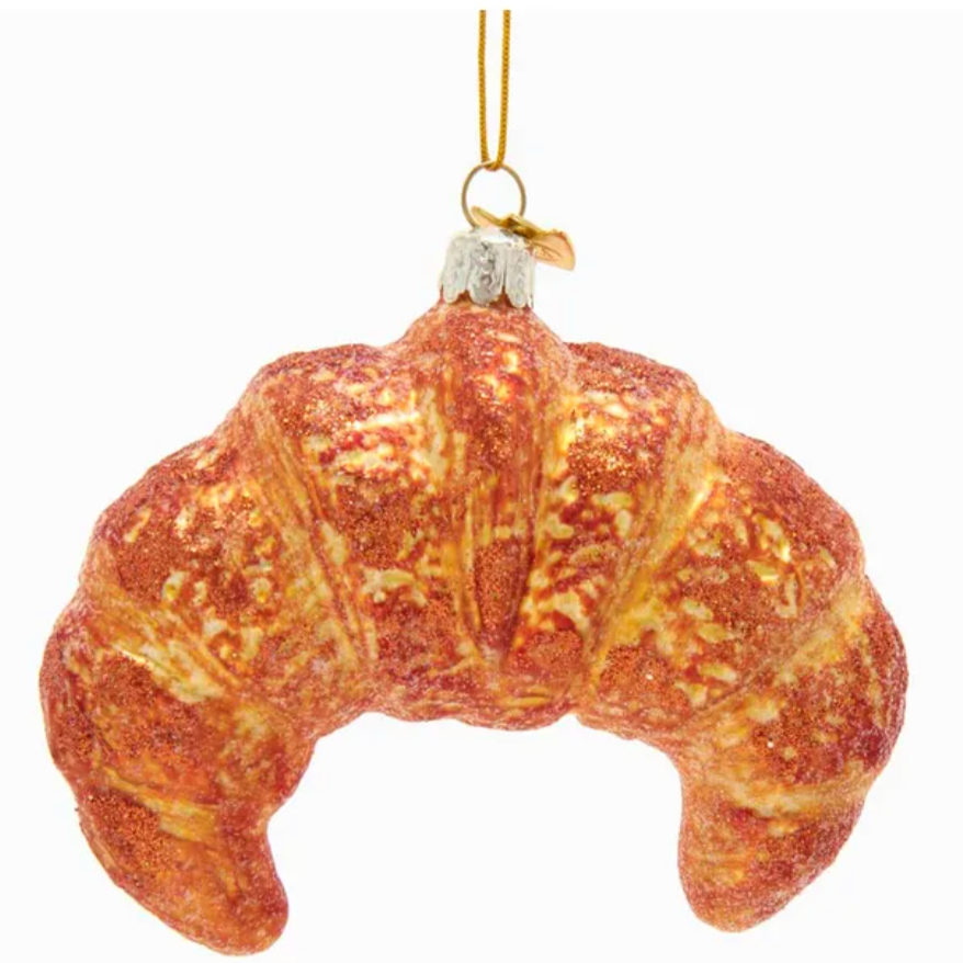 This image features a croissant-shaped ornament. The ornament is designed to look like a freshly baked croissant, with a golden-brown color and detailed texture to resemble its flaky, buttery layers. A gold string is attached at the top for hanging, making it a playful and charming decoration, possibly for a Christmas tree or as part of a food-themed collection.






