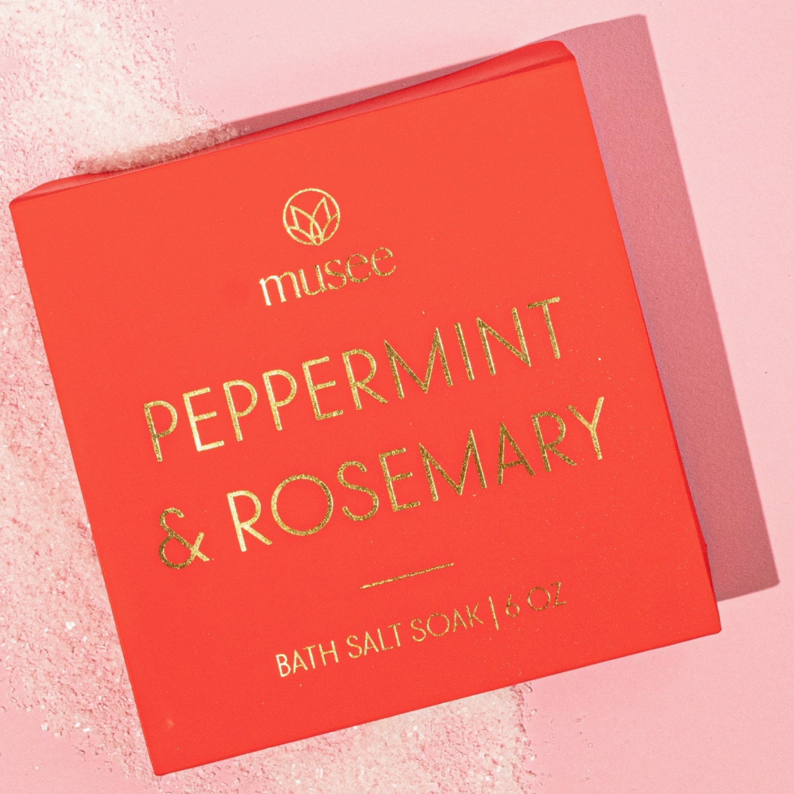 red box of bath salt soak that reads musee peppermint & rosemary in gold writing on pink background with salt visible 