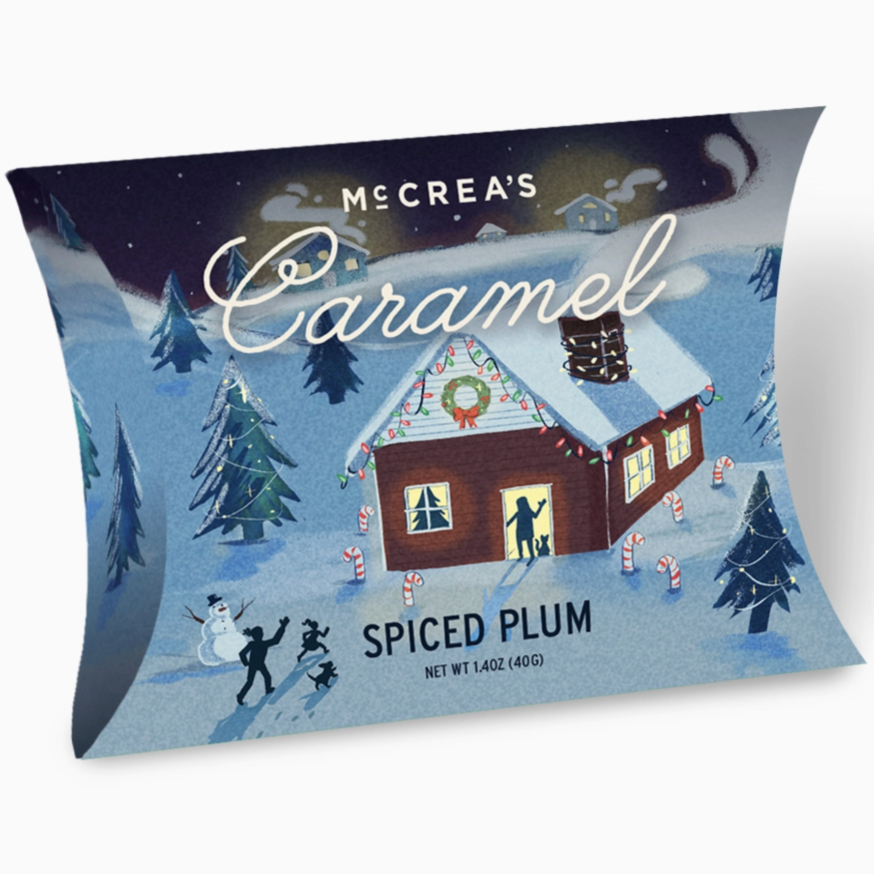 mccrea's pillow box of spiced plum caramels. packaging is decorated with snow, a house decorated for christmas, candy canes, christmas trees. 1.4 oz. box pictured behind white background. 