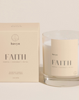 pale beige candle packaging by HAVYN that says FAITH SANTAL COCONUT PETAL next to clear glass candle on the right 