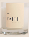 candle with beige on it by havyn that says faith santal coconut petal candle is clear with white wax 