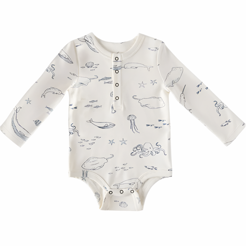 image of a baby bodysuit or onesie with an ocean or sea life-themed print. It has illustrations of whales, jellyfish, fish, and octopuses in soft, minimal colors. The design includes long sleeves and a front button placket with snaps at the bottom for easy changing.