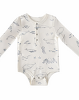 image of a baby bodysuit or onesie with an ocean or sea life-themed print. It has illustrations of whales, jellyfish, fish, and octopuses in soft, minimal colors. The design includes long sleeves and a front button placket with snaps at the bottom for easy changing.