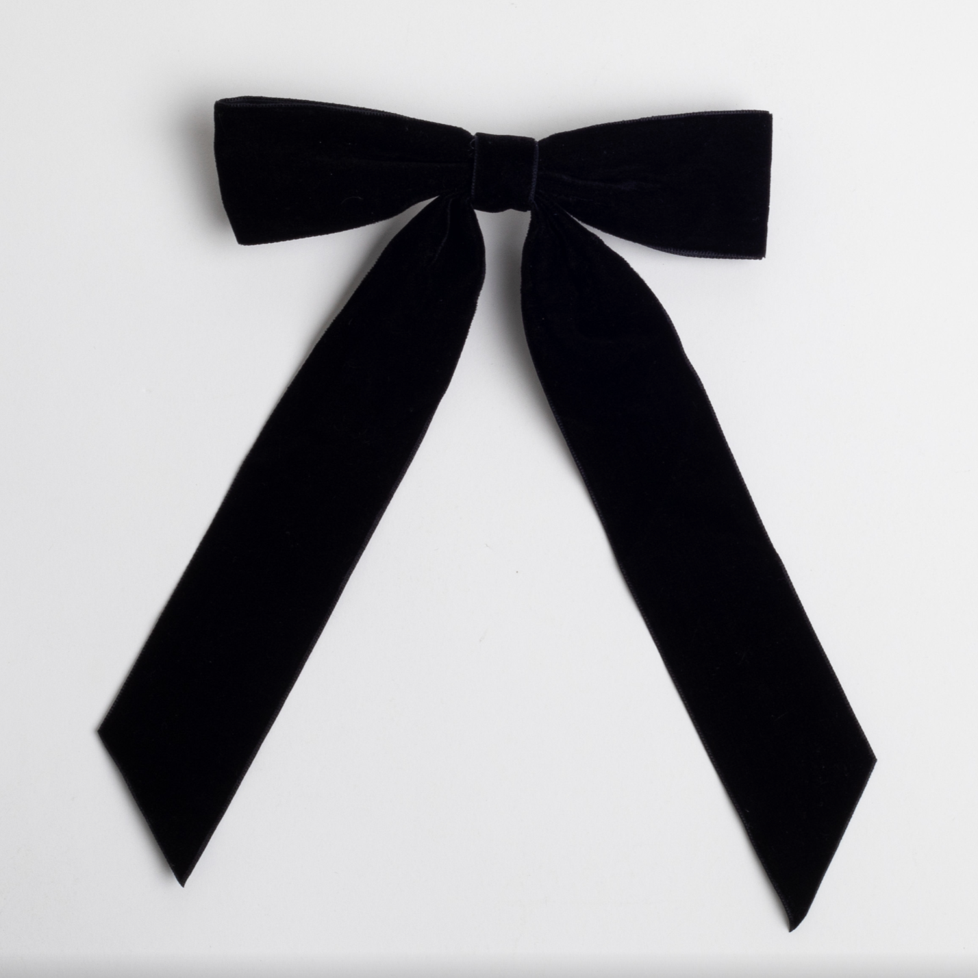 This image features a black velvet bow with long tails. The bow has a soft, luxurious texture, tied neatly in the center.