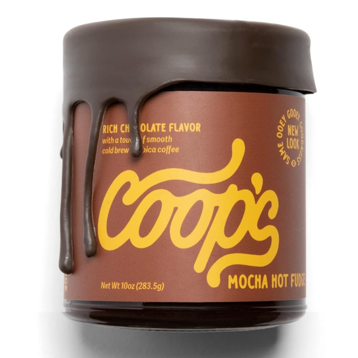 This image is of a jar labeled "Coop's Mocha Hot Fudge." The packaging is brown with yellow lettering, and it features a lid with chocolate-like drips down the side, giving it a melted chocolate appearance. The label mentions a rich chocolate flavor with hints of cold brew Arabica coffee. 