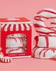 NCLA BEAUTY WRITTEN IN WHITE IN RED CHRISTMAS PACKAGING. THE ITEM IS A WHITE BATH TREAT WITH RED STRIPES ON A PINK BACKGROUND
