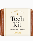 Close-up of a brown tech kit labeled '8 Essentials - Tech Kit for Taking Charge - Pinch Provisions,' showcasing a compact and stylish product with a gold zipper on a plain white background.