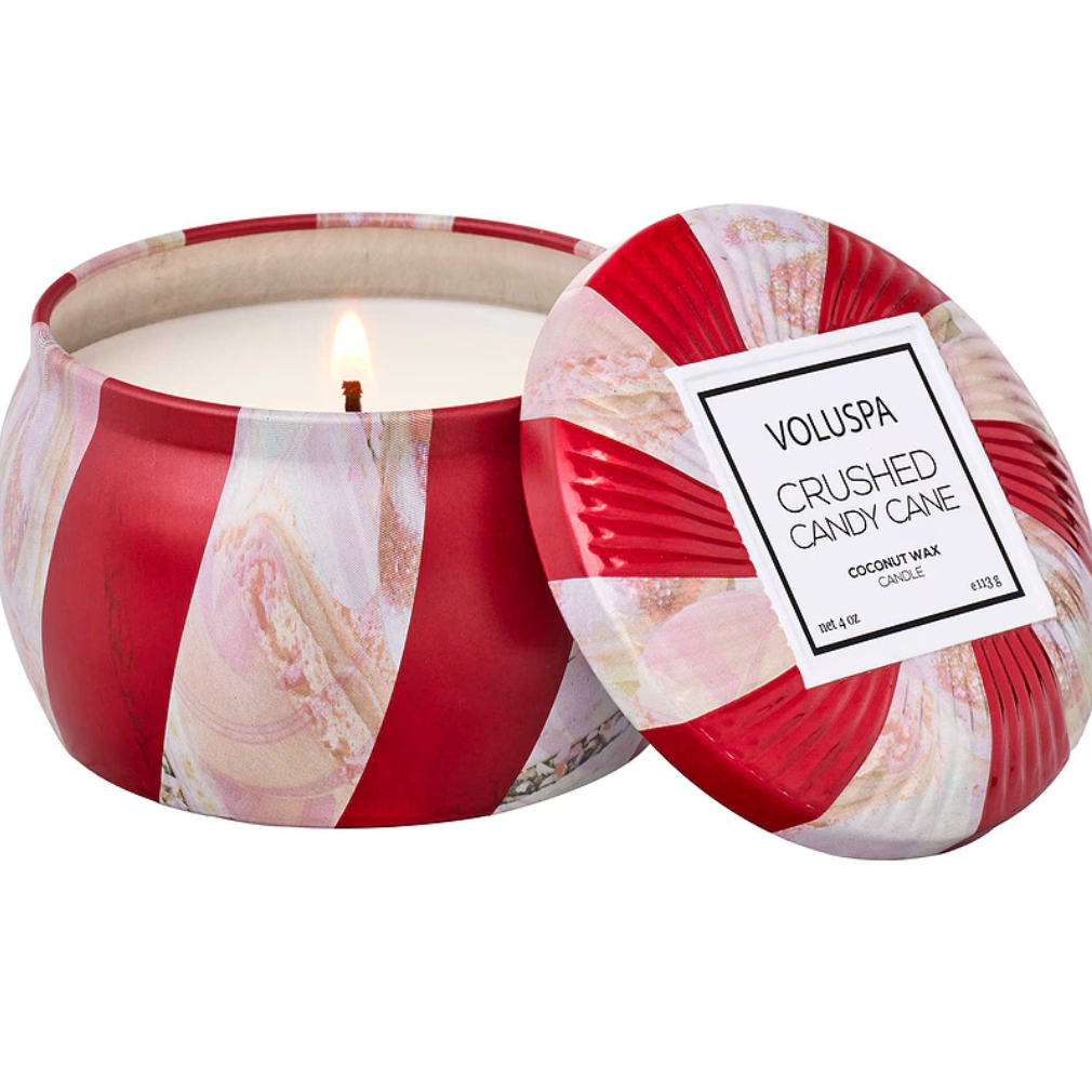 VOLUSPA CRUSHED CANDY CANE TIN CANDLE DISPLAYED OPEN, THE CANDLE HAS RED AND WHITE STRIPES