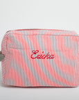 bright red & white striped makeup bag embroidered in red with the name 'Ericka'