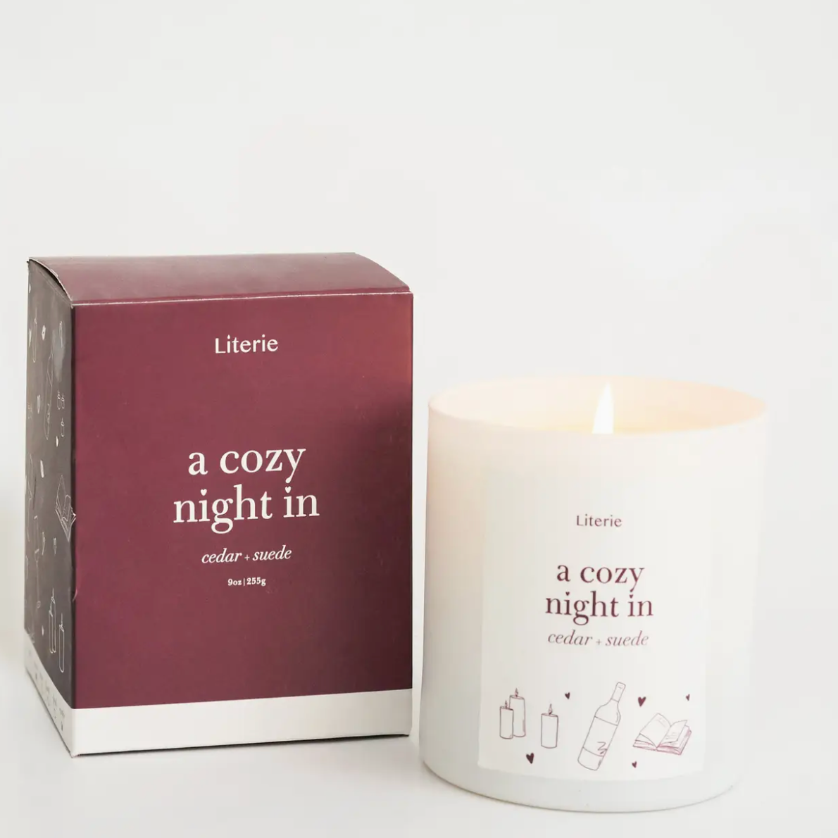 Lit candle and packaging of 'Literie' candle with text 'a cozy night in' on a white background