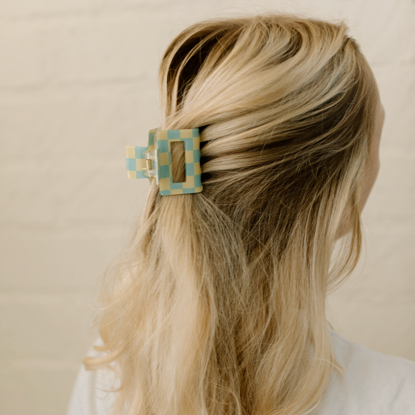 Blonde hair with a decorative hair clip against a beige background