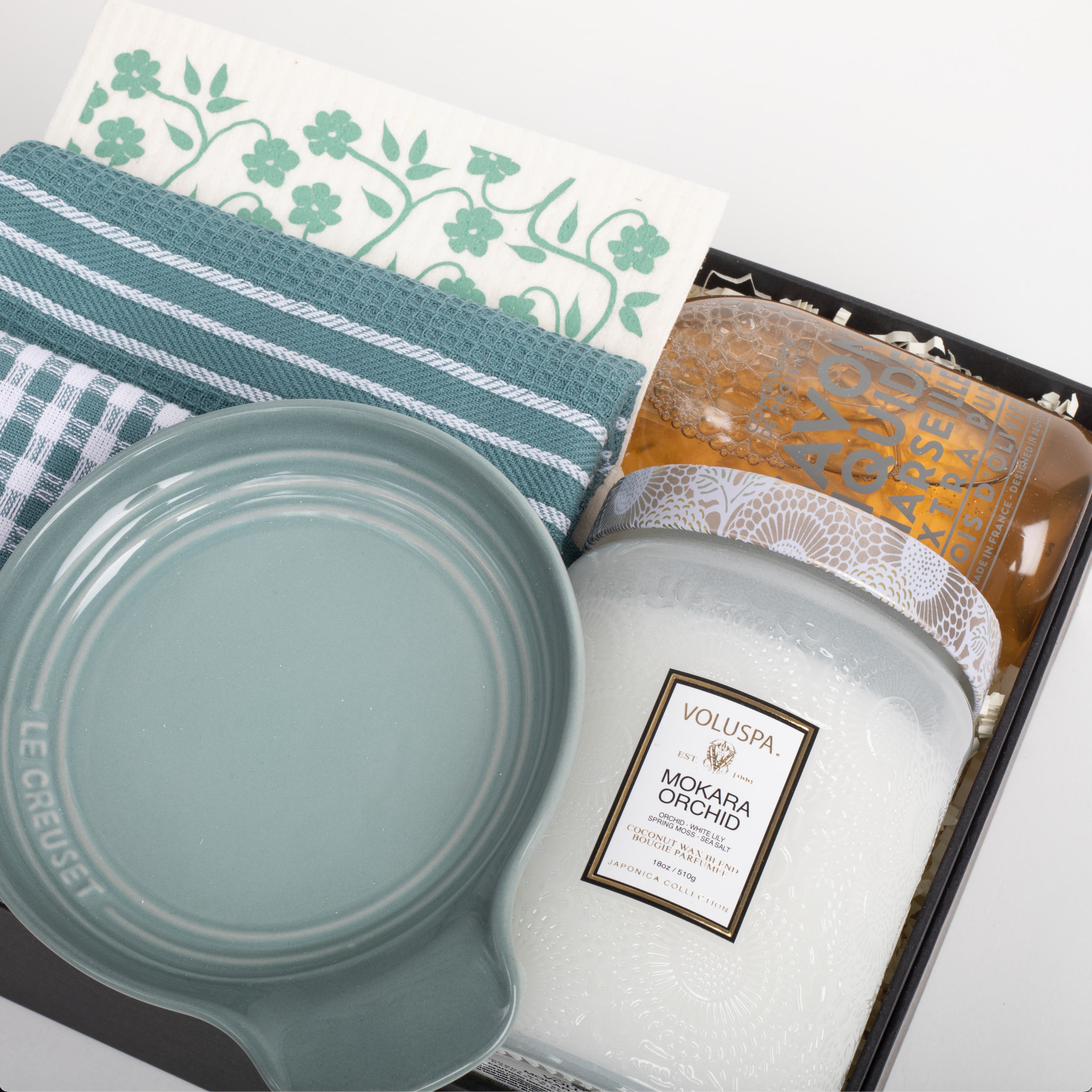 Candle, Le Creuset dish, and Voluspa packaging on a white surface