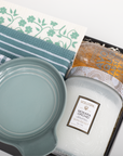 Candle, Le Creuset dish, and Voluspa packaging on a white surface