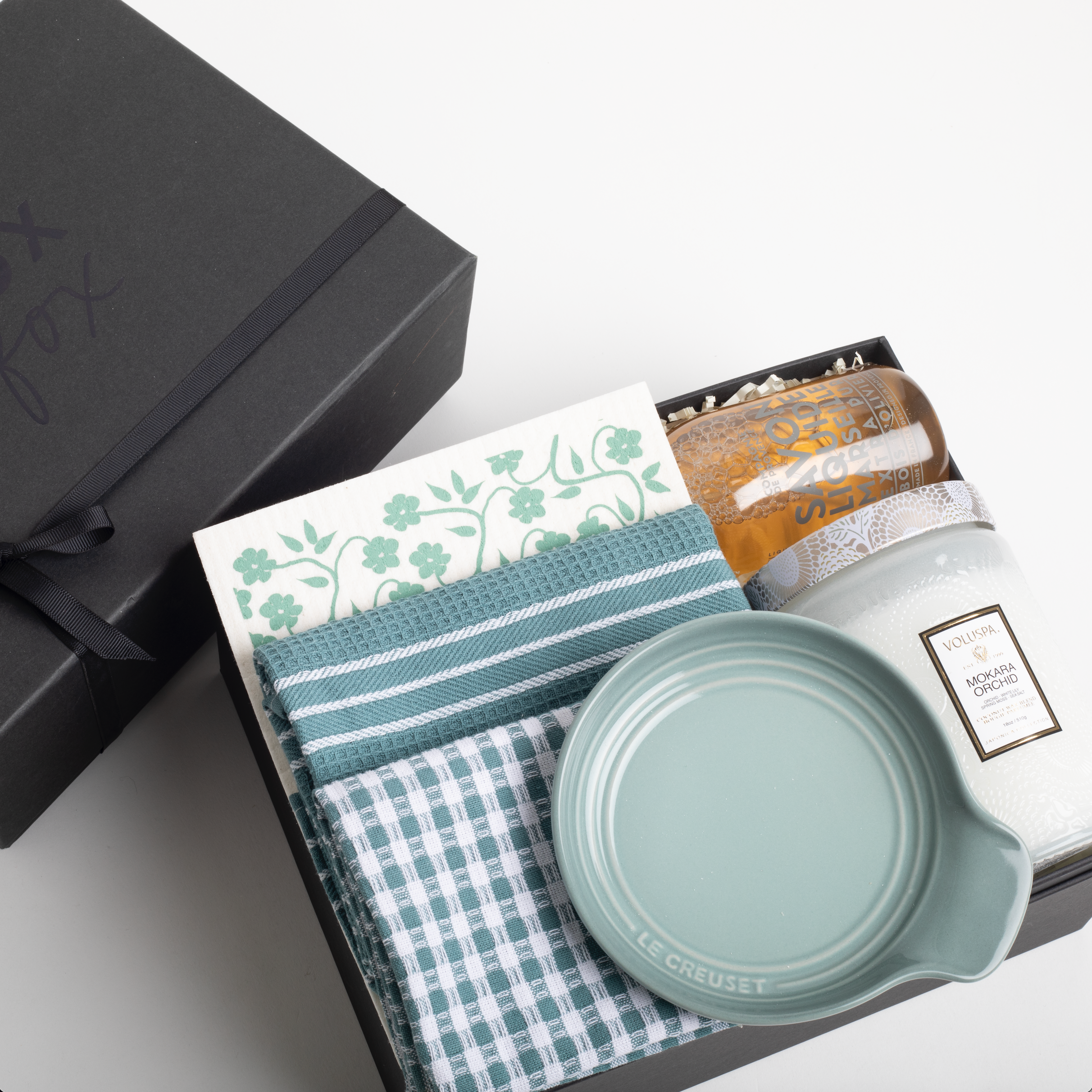 Gift set with a mug, towel, and other items in a black box on a white background