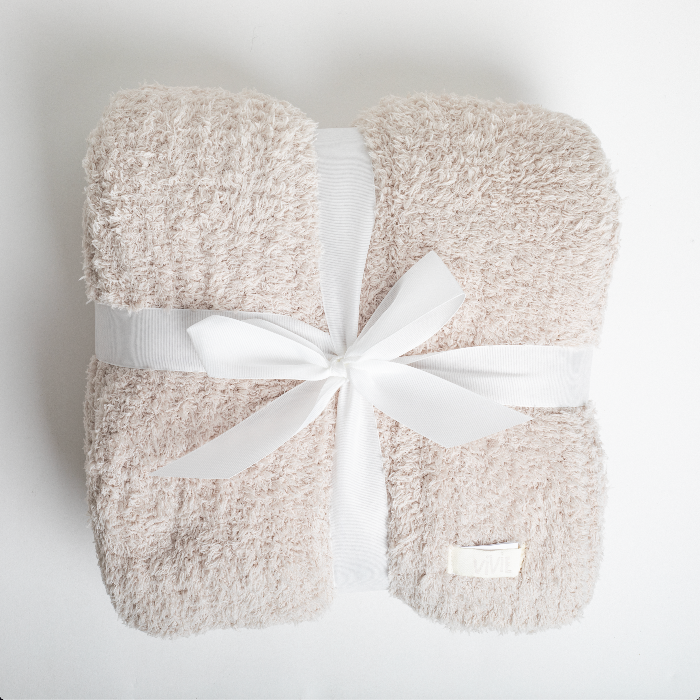 Beige blanket with a white bow on a light gray background