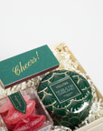 Decorative candle and candy set in a gift box with 'Cheers!' card on a white background