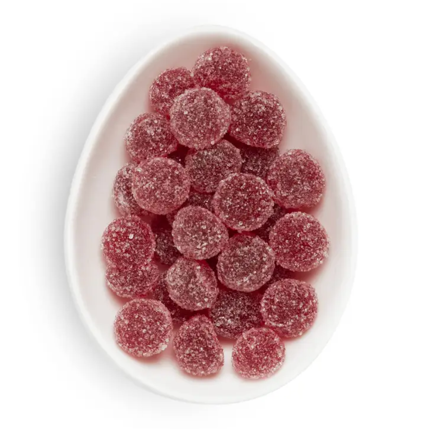 White bowl filled with red gummy candies on a white background