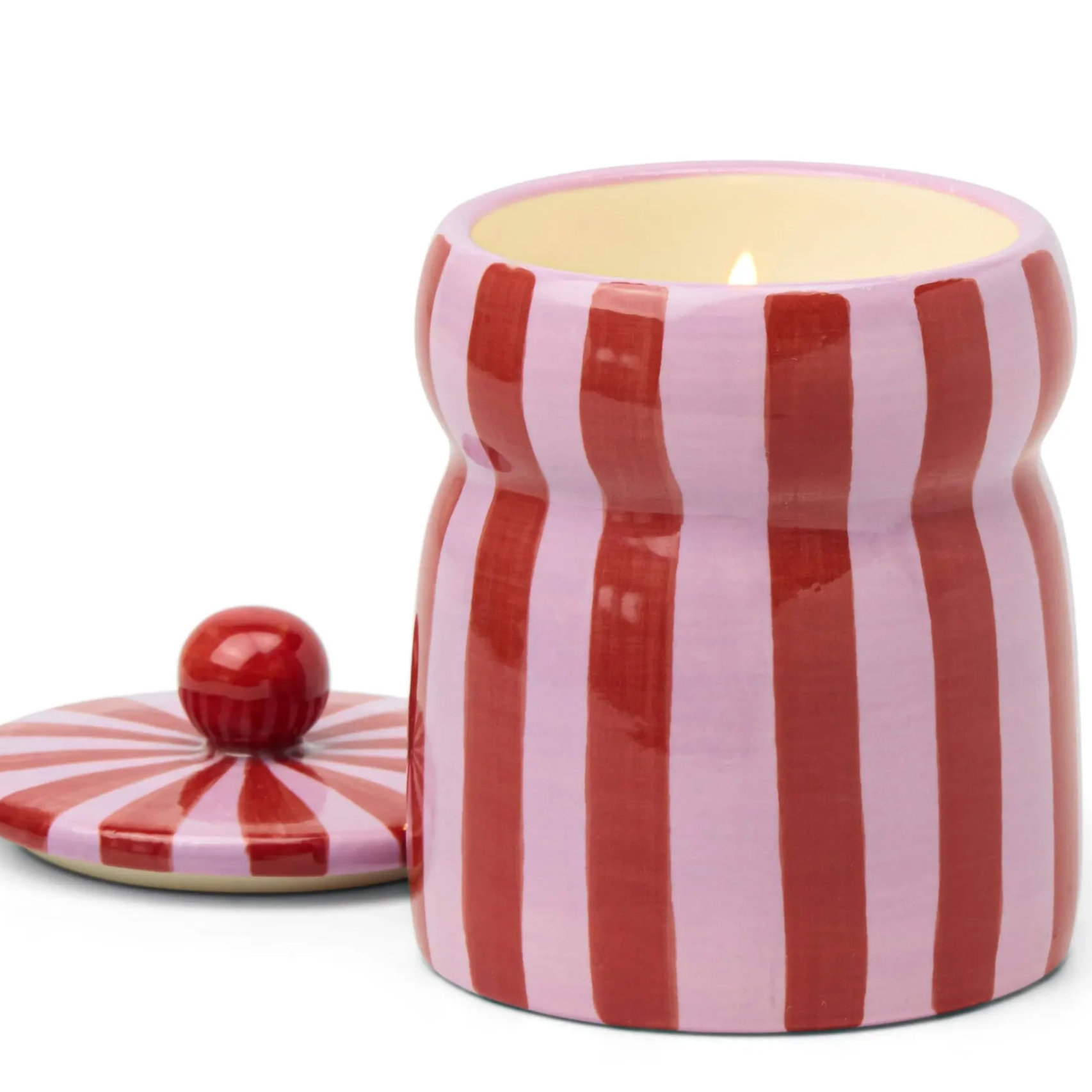 Striped ceramic jar with a candle inside on a white background