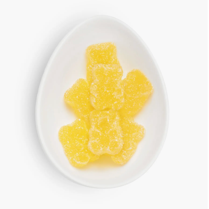 Yellow gummy bear on a white plate with a white background