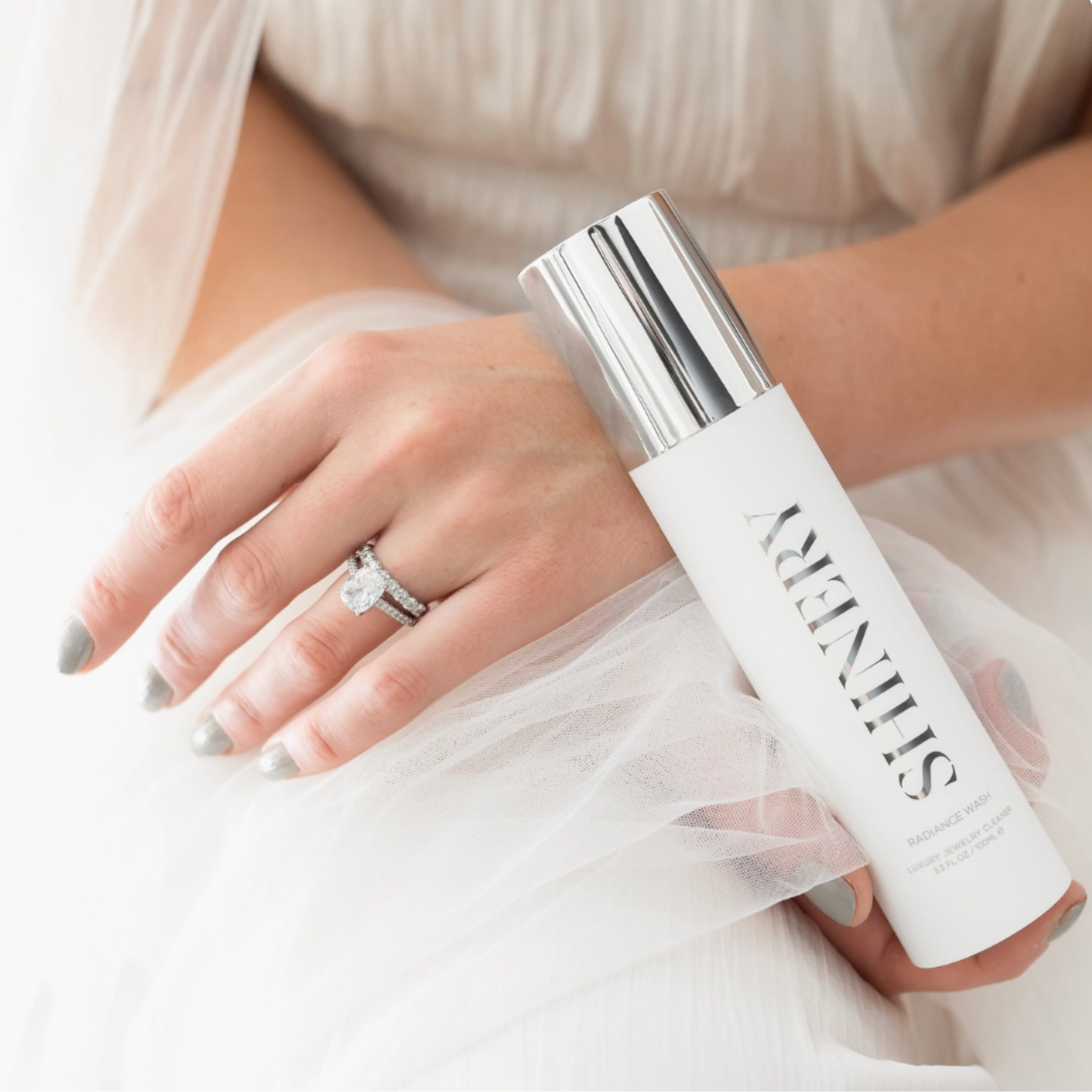 Person holding a white skincare bottle labeled 'SeneGence' with a blurred background