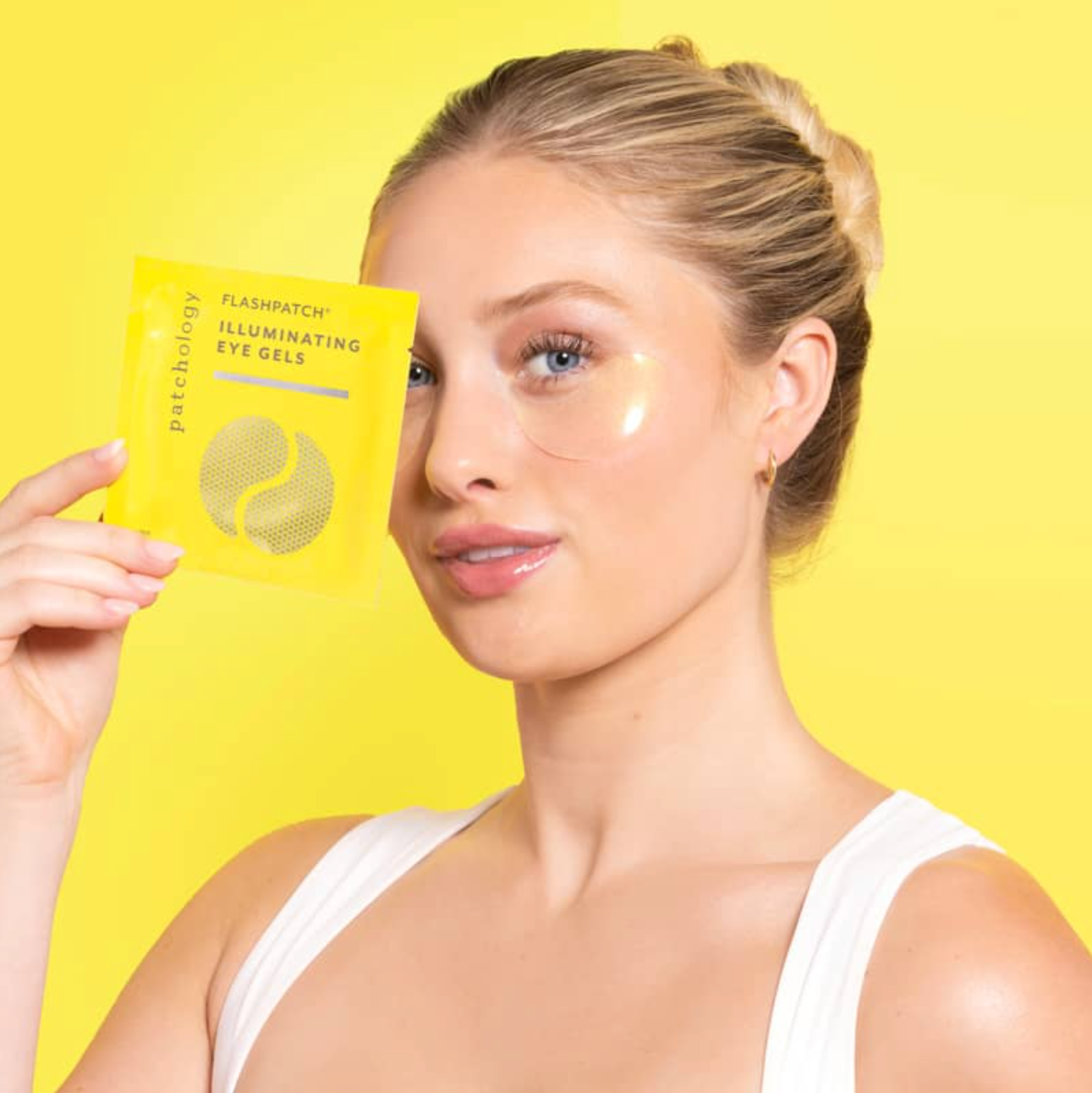 Woman with eye gels under eyes holding a package against a yellow background